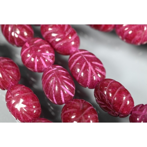 281 - A triple row of graduated carved ruby beads on silk cord, 1 x 0.8 cm the smallest, 1.5 x 1.3 cm the ... 