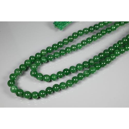 282 - A double row of uniform round emerald beads, on silk cord, 0.8 cm diam