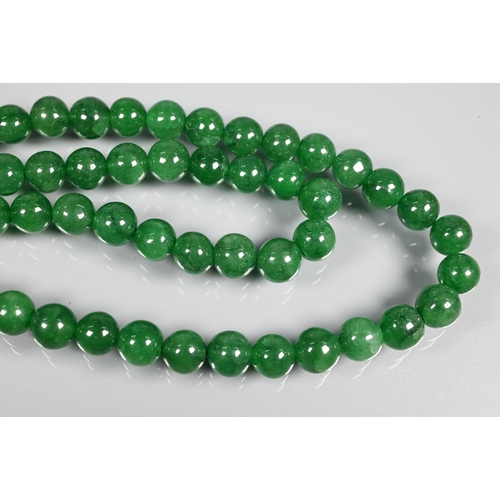 282 - A double row of uniform round emerald beads, on silk cord, 0.8 cm diam