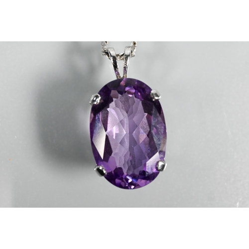 287 - An oval amethyst pendant in claw setting on flat linked white metal chain stamped 750, approx 5.9g (... 