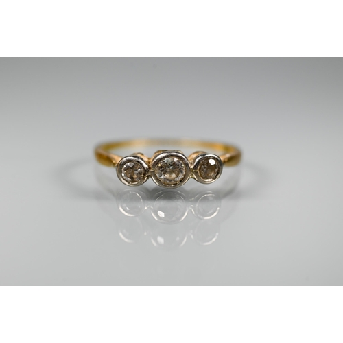 297 - An antique three stone diamond ring, the graduated diamonds in bezel settings, yellow gold set (mark... 