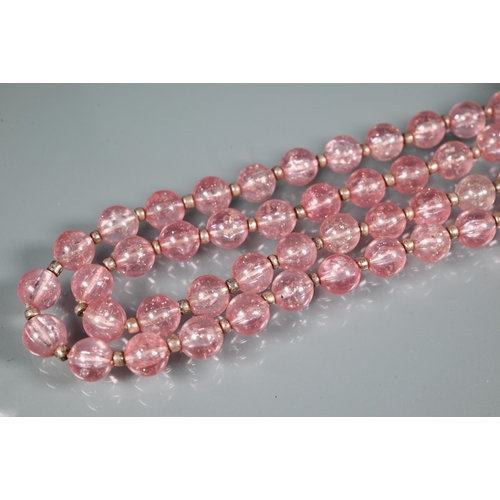 301 - An eary 20th century necklace formed of rose quartz ovoid drops from an oval centrepiece on white me... 