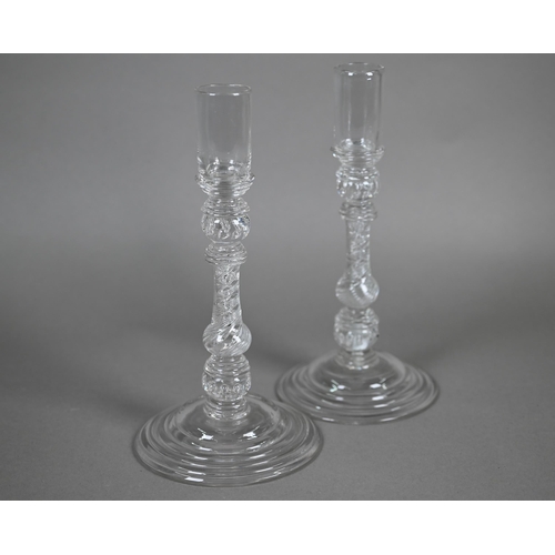 528 - A pair of antique glass candlesticks with plain cylindrical sockets on baluster stems with bubbles a... 