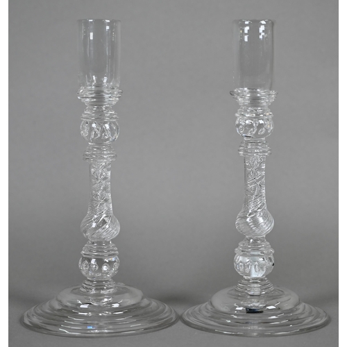 528 - A pair of antique glass candlesticks with plain cylindrical sockets on baluster stems with bubbles a... 