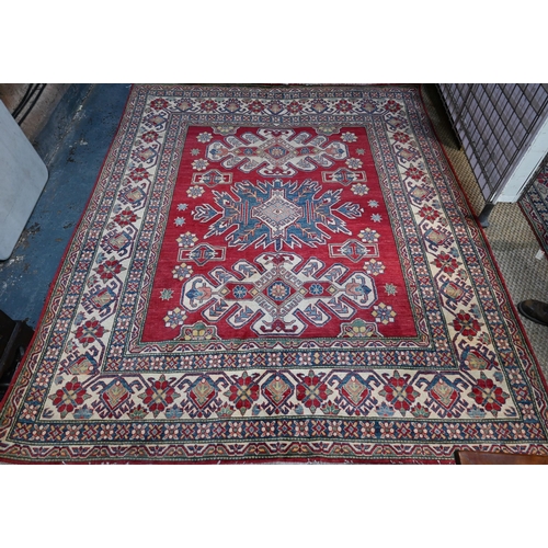 800 - A contemporary Kazak carpet with pale red ground and stylized floral design within camel ground bord... 