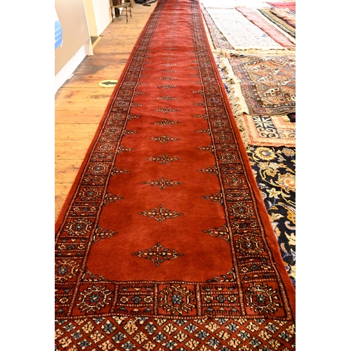 806 - A Bokhara long red ground runner of repeating designs, 629 x 79 cm