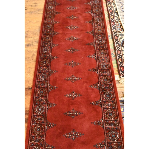 806 - A Bokhara long red ground runner of repeating designs, 629 x 79 cm