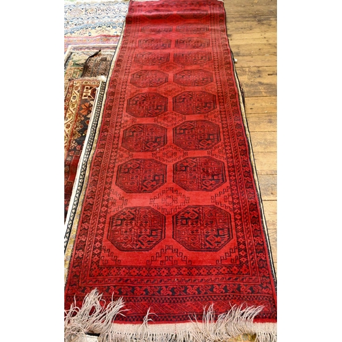 812 - An Afghan red ground runner with two rows of guls, 320 cm x 91 cm