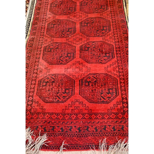 812 - An Afghan red ground runner with two rows of guls, 320 cm x 91 cm