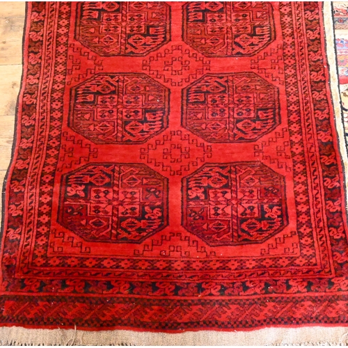 812 - An Afghan red ground runner with two rows of guls, 320 cm x 91 cm