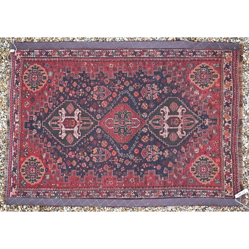 817 - A Persian Shiraz rug, the triple lozenge design on blue-brown ground, 162 cm x 116 cm