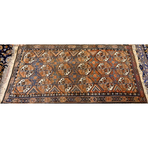 826 - An antique Kurdish rug runner, the field of octagonal tiles on blue-brown ground, 226 cm x 117 cm