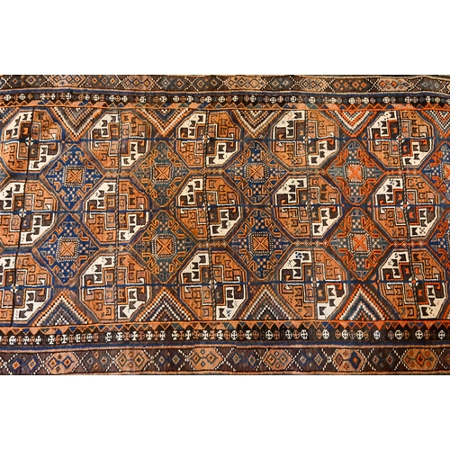 826 - An antique Kurdish rug runner, the field of octagonal tiles on blue-brown ground, 226 cm x 117 cm