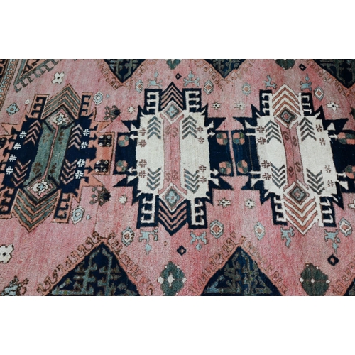 827 - A mid-century Turkish rug, faded red ground rug with geometric design, 228 cm x 164 cm