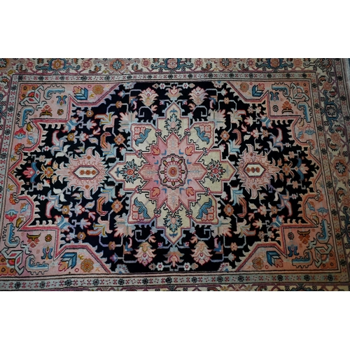 830 - A contemporary North West Persian Heriz rug, the pink design on black ground, 195 cm x 145 cm