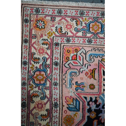 830 - A contemporary North West Persian Heriz rug, the pink design on black ground, 195 cm x 145 cm