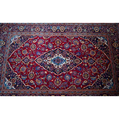 832 - An old central Persian Kashan rug, the wine-red ground centred by a blue ground floral medallion, 21... 