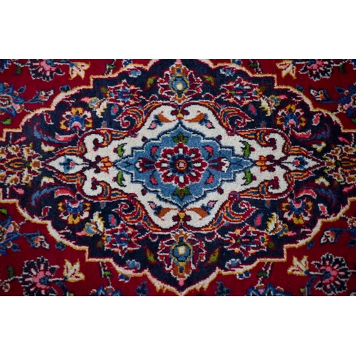 832 - An old central Persian Kashan rug, the wine-red ground centred by a blue ground floral medallion, 21... 