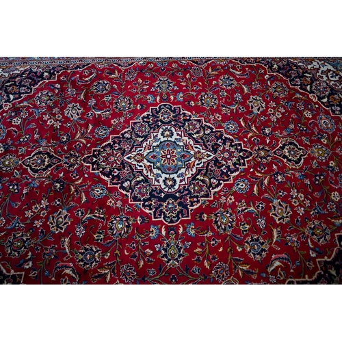 840 - A contemporary central Persian Kashan carpet, the red and blue ground with floral vines centred by a... 