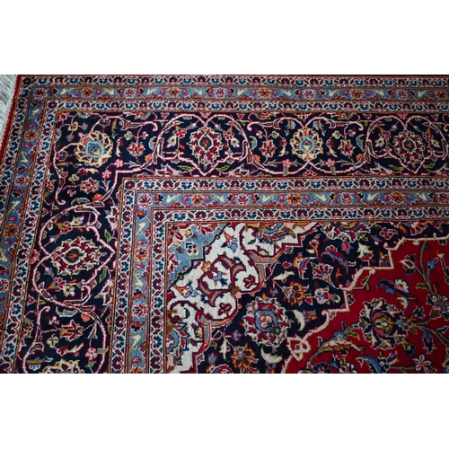 840 - A contemporary central Persian Kashan carpet, the red and blue ground with floral vines centred by a... 