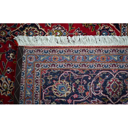 840 - A contemporary central Persian Kashan carpet, the red and blue ground with floral vines centred by a... 