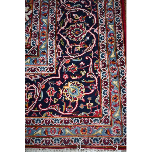 840 - A contemporary central Persian Kashan carpet, the red and blue ground with floral vines centred by a... 