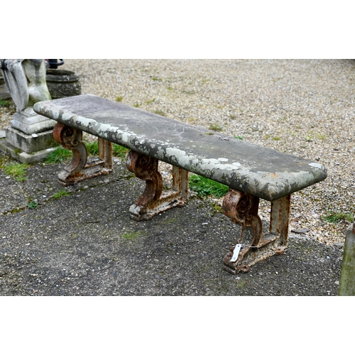 897 - A weathered antique stone and cast iron garden bench, the rectangular seat raised on three decorativ... 