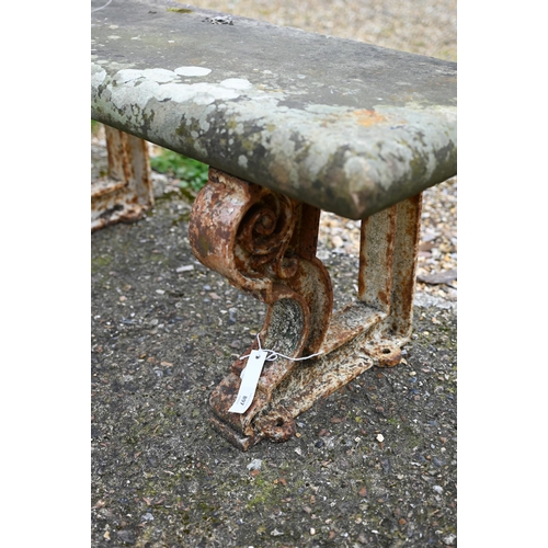 897 - A weathered antique stone and cast iron garden bench, the rectangular seat raised on three decorativ... 