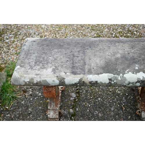 897 - A weathered antique stone and cast iron garden bench, the rectangular seat raised on three decorativ... 