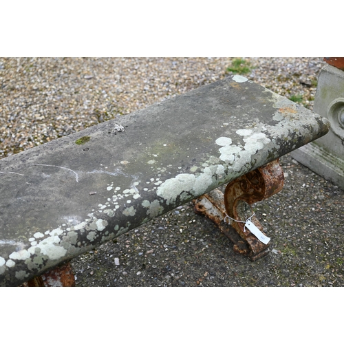 897 - A weathered antique stone and cast iron garden bench, the rectangular seat raised on three decorativ... 