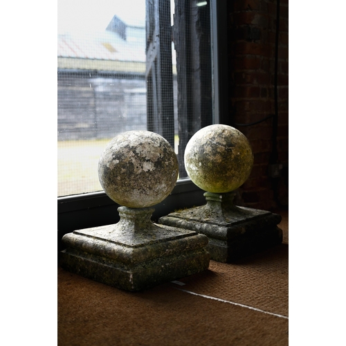 899 - A pair of large weathered old cast stone spherical finials, raised on square socle bases, 40 cm x 40... 