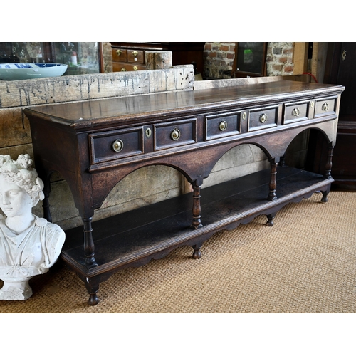 925 - An antique oak low dresser with three double moulded front drawers over a triple arched apron, raise... 