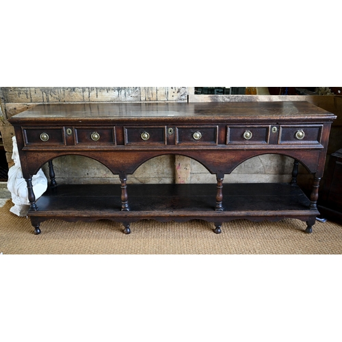 925 - An antique oak low dresser with three double moulded front drawers over a triple arched apron, raise... 