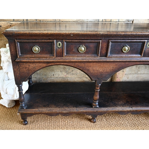 925 - An antique oak low dresser with three double moulded front drawers over a triple arched apron, raise... 