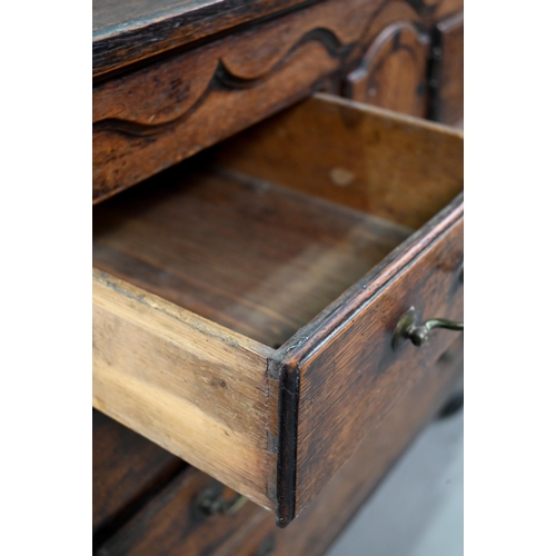 929 - An 18th century oak chest, the wavy frieze over a centre cupboard flanked by short two tier drawers,... 