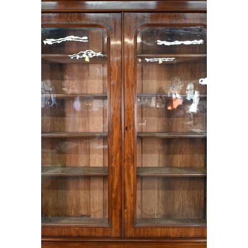 933 - A late Victorian mahogany library cabinet bookcase, the pair of arched glazed doors over a conformin... 