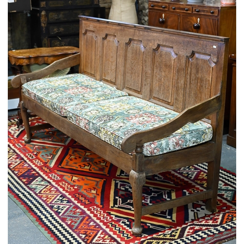 937 - A George III oak settle, the panelled back with shapes arms over a wood slat seat (and loose cushion... 