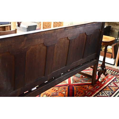 937 - A George III oak settle, the panelled back with shapes arms over a wood slat seat (and loose cushion... 