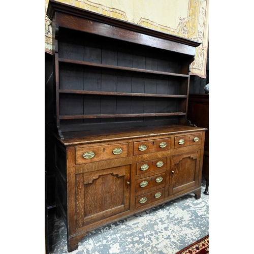 945 - An 18th century and later oak high dresser, the three tier rack with plank back over an arrangement ... 