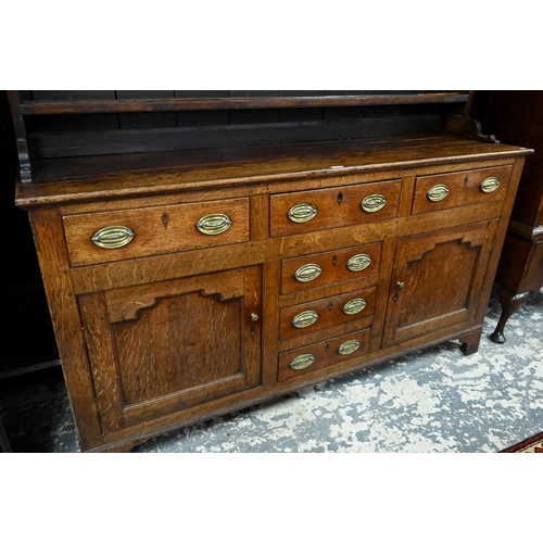 945 - An 18th century and later oak high dresser, the three tier rack with plank back over an arrangement ... 