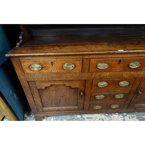 945 - An 18th century and later oak high dresser, the three tier rack with plank back over an arrangement ... 