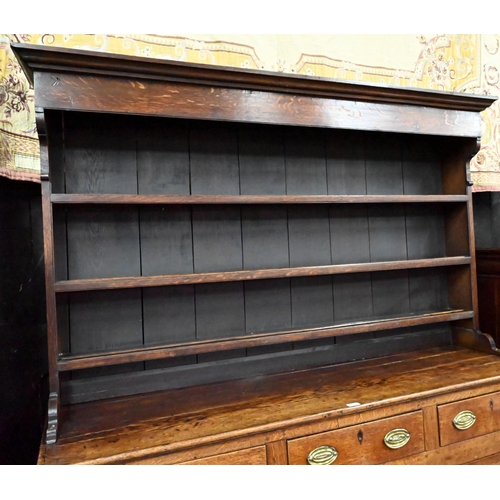 945 - An 18th century and later oak high dresser, the three tier rack with plank back over an arrangement ... 