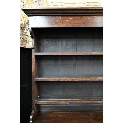 945 - An 18th century and later oak high dresser, the three tier rack with plank back over an arrangement ... 