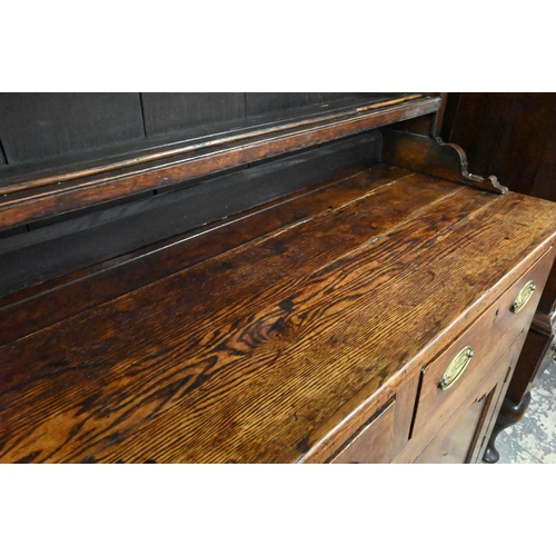 945 - An 18th century and later oak high dresser, the three tier rack with plank back over an arrangement ... 