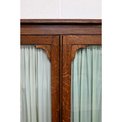 121 - Oak bookcase with glazed doors enclosing three fixed shelves, 102 x 32 x 152 cm high