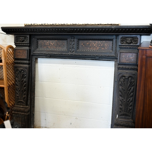 136 - An antique carved oak fire surround with iron masks and foliate marquetry panels, 104 cm high x 100 ... 