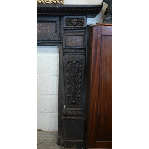 136 - An antique carved oak fire surround with iron masks and foliate marquetry panels, 104 cm high x 100 ... 