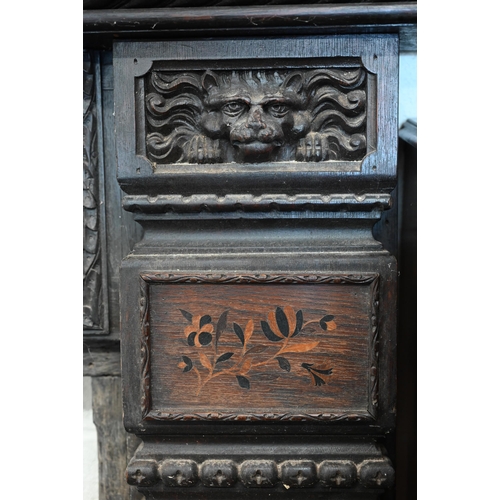 136 - An antique carved oak fire surround with iron masks and foliate marquetry panels, 104 cm high x 100 ... 