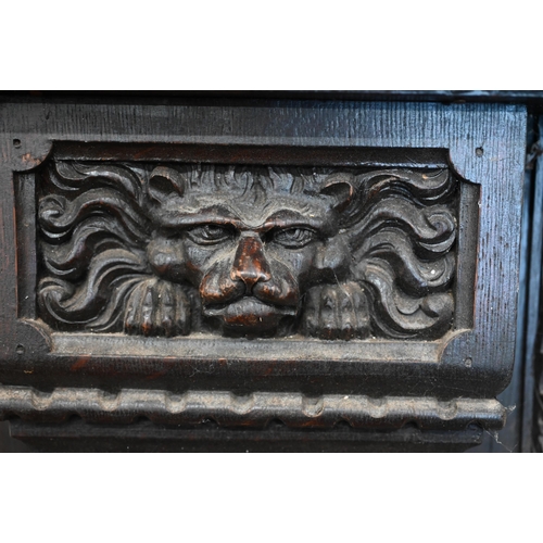 136 - An antique carved oak fire surround with iron masks and foliate marquetry panels, 104 cm high x 100 ... 