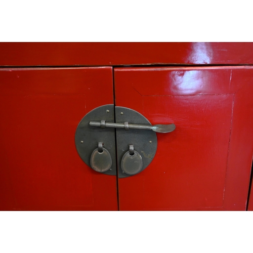 137 - A Chinese red lacquer sidetable with central cupboards and two drawers to each side, with brass fitt... 